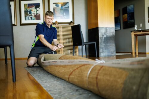 Premier Oriental Rug Cleaning technician delivering a rolled rug to a Chicago customer cleaned area rug delivery to a Chicago customer