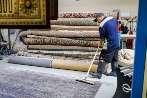 Technician grooming a cleaned area rug before delivery to Chicago customers final rug grooming after cleaning
